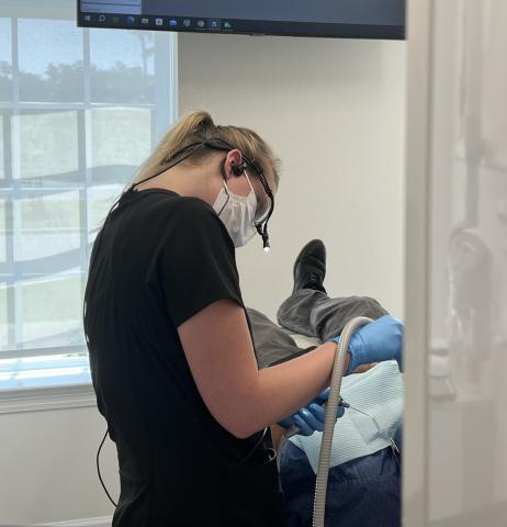 Dental assistant wearing a mask during a patient's exam. 