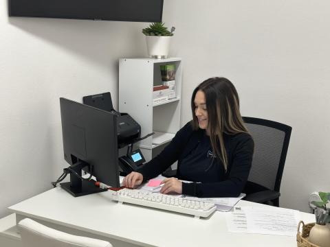 Treatment Coordinator in her office typing at a computer. 