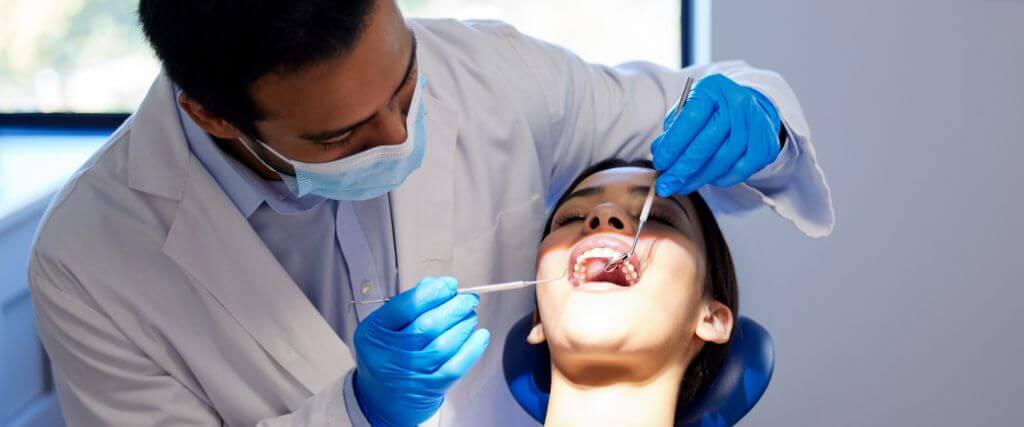 Male dentist performing dental work on female patient 